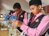 Two male school pupils have a go at using water quality testing kits, using beakers, pipettes, and other basic lab equipment thumbnail